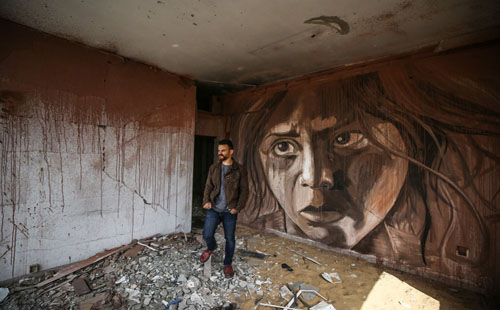 فنان فلسطيني يبدع في رسم لوحات على بقايا جدران بنايات غزة المدمرة